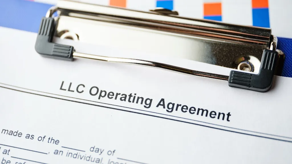 Close-up of a printed LLC Operating Agreement document secured on a metal clipboard.