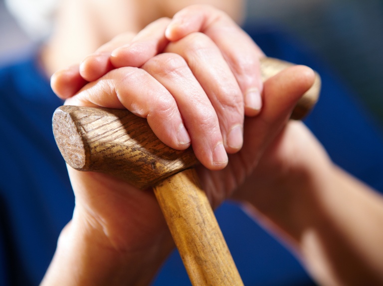 Elderly person clutching a cane