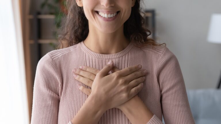 Happy woman holding hands on heart