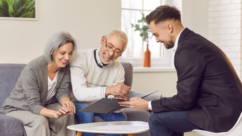 happy smiling senior couple sitting on sofa with lawyer