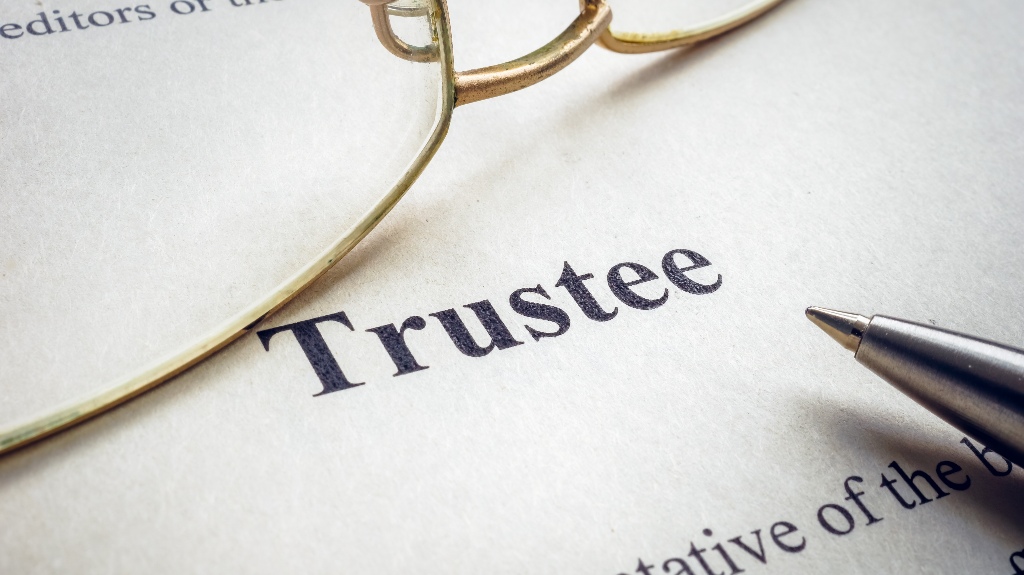Word trustee near glasses and a pen