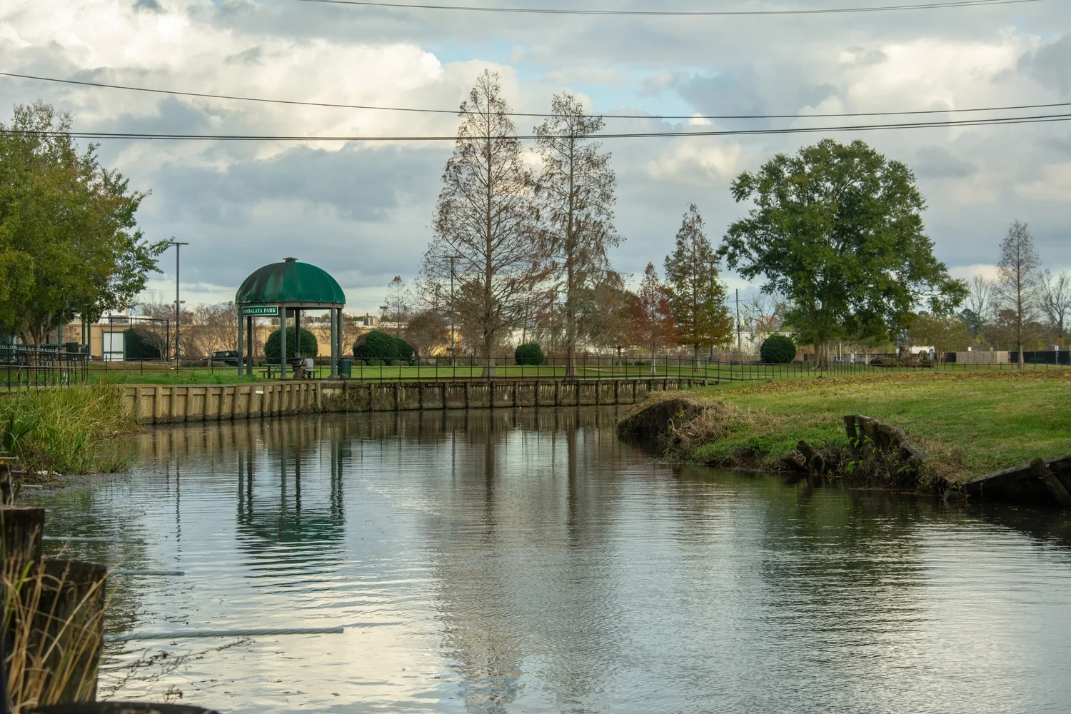 A serene body of water reflecting the sky, surrounded by lush greenery and distant hills
