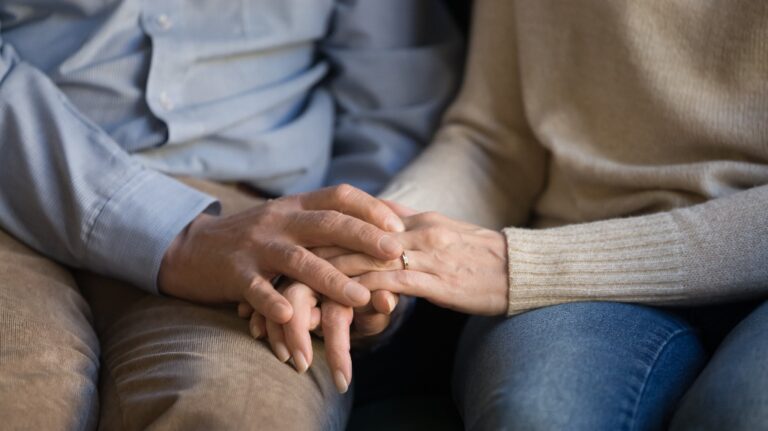family couple sitting on sofa, holding hands