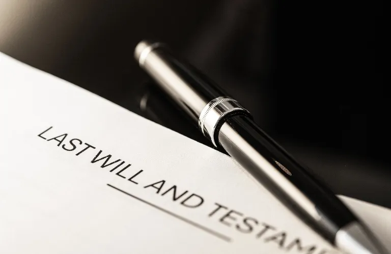 Close-up of a black and silver pen resting on a "Last Will and Testament" document.