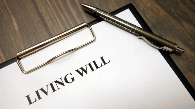 Clipboard with a living will document and a metallic pen on a wooden surface.