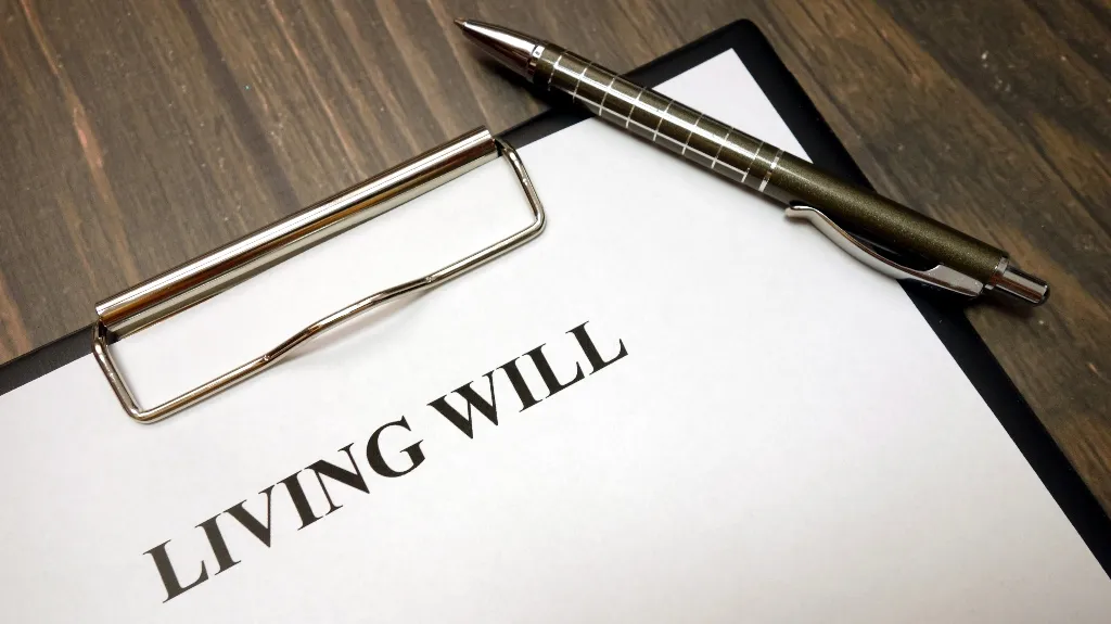 Clipboard with a living will document and a metallic pen on a wooden surface.