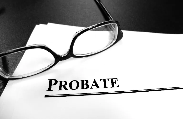 Close-up of a document titled "PROBATE" with black-framed eyeglasses resting on top.